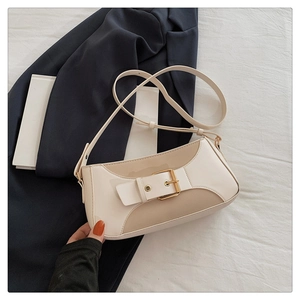 Detail of two-tone shoulder bag with metal buckle on navy blazer background