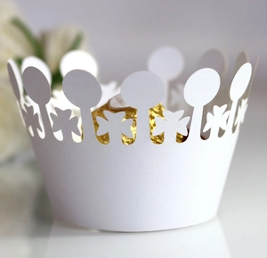 Detail of white laser-cut crown cupcake wrapper with delicate clover hollow patterns