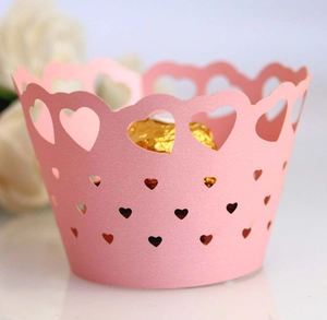 Detailed view of pink laser-cut cupcake wrapper with heart patterns and gold chocolate