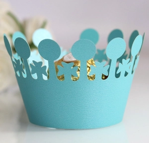 Macro view of laser-cut light blue pearl paper cupcake wrappers with crown edge