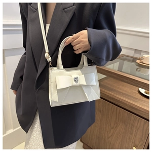 Dettaglio della borsa a tracolla bianco crema con fiocco e strass a cuore sulla pelle