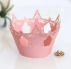 Detail of pink pearlescent laser-cut cupcake wrapper with star patterns and crown edges
