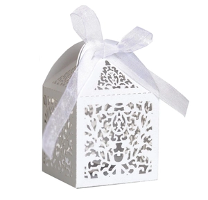 Detail of white laser-cut wedding favor box with elegant pattern and organza ribbon