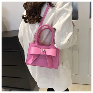 Borsa a mano rosa con fiocco e diamante a cuore indossata come borsa a tracolla