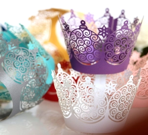 Macro shot of laser-cut crown cake wrappers with intricate scroll patterns in assorted colors