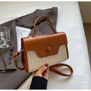 Close-up of brown leather and woven straw crossbody bag against a lifestyle background