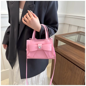 Dettaglio della borsa rosa con fiocco e cristallo a cuore su outfit con blazer