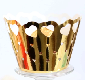 Detailed close-up of golden laser-cut cupcake wrappers with romantic heart patterns