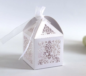 Close-up of laser-cut hollow pattern and white satin bow on high-quality wedding favor box