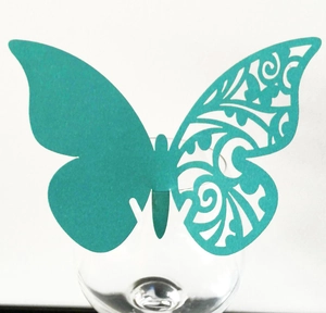 Detail of laser-cut butterfly cup card in teal color for wedding table decoration