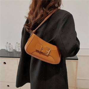 Vintage brown leather baguette bag with metal buckle strap worn on the shoulder