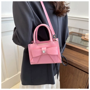 Dettaglio della borsa rosa con fiocco e cristallo a cuore su blazer grigio