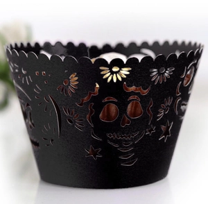 Macro shot of laser-cut black cupcake wrapper with skull and sunflower patterns