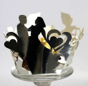 Detail of silver laser-cut cupcake wrapper with bride and groom silhouette heart design