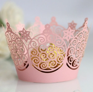 Pink laser-cut crown cupcake wrapper with intricate patterns for festive wedding decorations