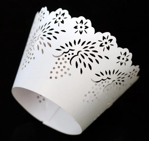 Detail showing white laser-cut floral patterns on a cupcake wrapper with scalloped edges