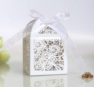 Close-up of white laser-cut floral favor box with an elegant white silk ribbon bow