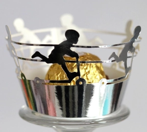 Laser-cut silver cupcake wrapper featuring outdoor activity silhouettes for children