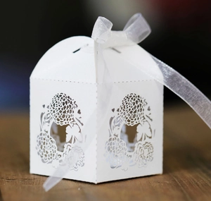 Elegant white laser-cut hollow floral wedding favor box with a delicate white ribbon