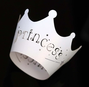Detail of white laser-cut princess crown cake wrapper with elegant black lettering