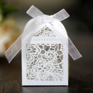 Detailed view of white laser-cut floral wedding favor box with a satin ribbon bow