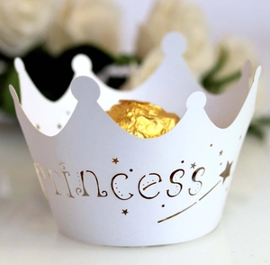 Macro shot of white princess crown paper cupcake wrapper with laser-cut gold star details
