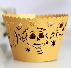 Macro shot of yellow cupcake wrappers with laser-cut skull and floral hollow patterns