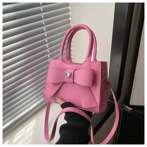 Dettaglio della borsa rosa con fiocco, strass a cuore e manico superiore