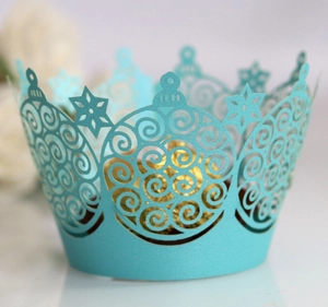 Laser-cut light blue cupcake wrappers with crown and snowflake patterns for wedding decor