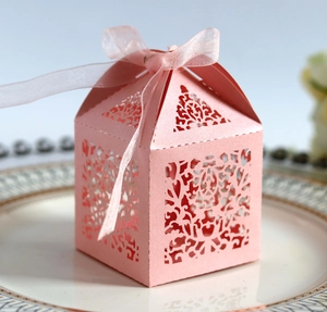 Detail of pink laser-cut wedding favor box with pearl paper texture and silk ribbon bow