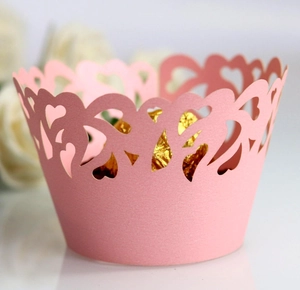 Macro shot of pink laser-cut heart pattern cupcake wrapper for wedding parties