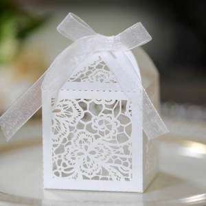 Close-up of laser-cut lace floral patterns on a white wedding favor box with ribbon