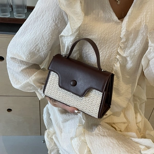 Elegant hand-woven straw crossbody bag with brown leather flap and stylish round buckle