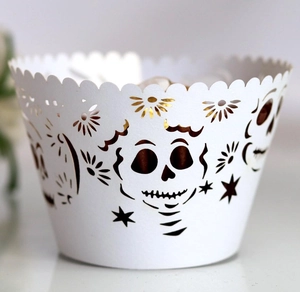 Detailed laser-cut white cupcake wrapper with intricate sugar skull and star patterns