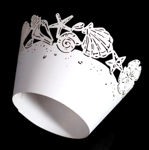 Macro view of white laser-cut cupcake wrappers with shell and starfish ocean patterns