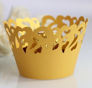 Macro shot of gold laser-cut cupcake wrappers with elegant hollow heart patterns