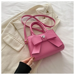 Dettaglio borsa rosa con fiocco e cristallo a cuore su blazer avorio, stile chic
