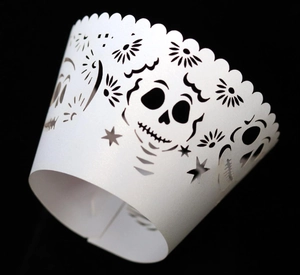 Detailed laser-cut white cupcake wrapper with skull pattern and scalloped edges