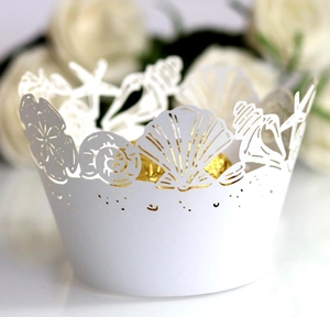 Close-up of laser-cut ocean theme cupcake wrappers with white shell and starfish patterns