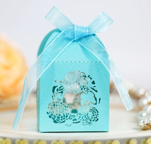 Detail of laser-cut sky blue favor box with intricate floral pattern and sheer ribbon