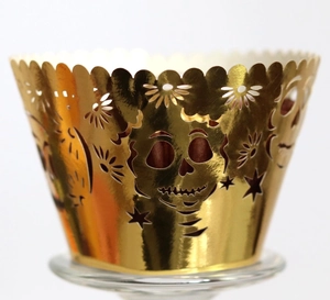 Detailed laser-cut golden cupcake wrapper featuring hollow skull and floral patterns