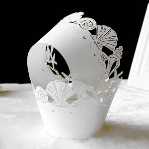 Detailed laser-cut white cupcake wrapper featuring ocean shells and coral patterns