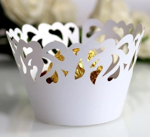 Detailed laser-cut heart pattern on white paper cupcake wrappers for wedding decor