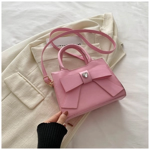 Dettaglio della borsa in pelle rosa con fiocco grande e cuore di cristallo su un blazer
