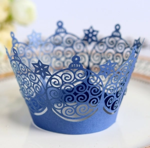 Blue laser-cut cupcake wrappers with snowflake crown design on a white ceramic plate