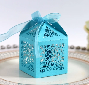 Close-up of laser-cut hollow pattern on light blue favor box with ribbon on a plate