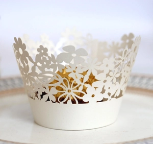 Detailed laser-cut white paper cupcake wrapper with floral pattern and gold chocolate