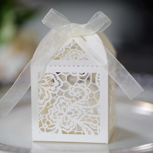 Detailed laser-cut flower patterns on white wedding favor box with a satin ribbon bow