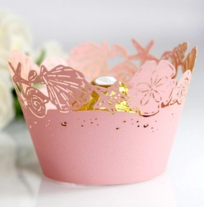 Detail of pink laser-cut cupcake wrapper with ocean motifs and pearl paper texture