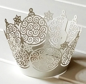 Detail of white laser-cut cupcake wrappers with Christmas ball and star hollow patterns